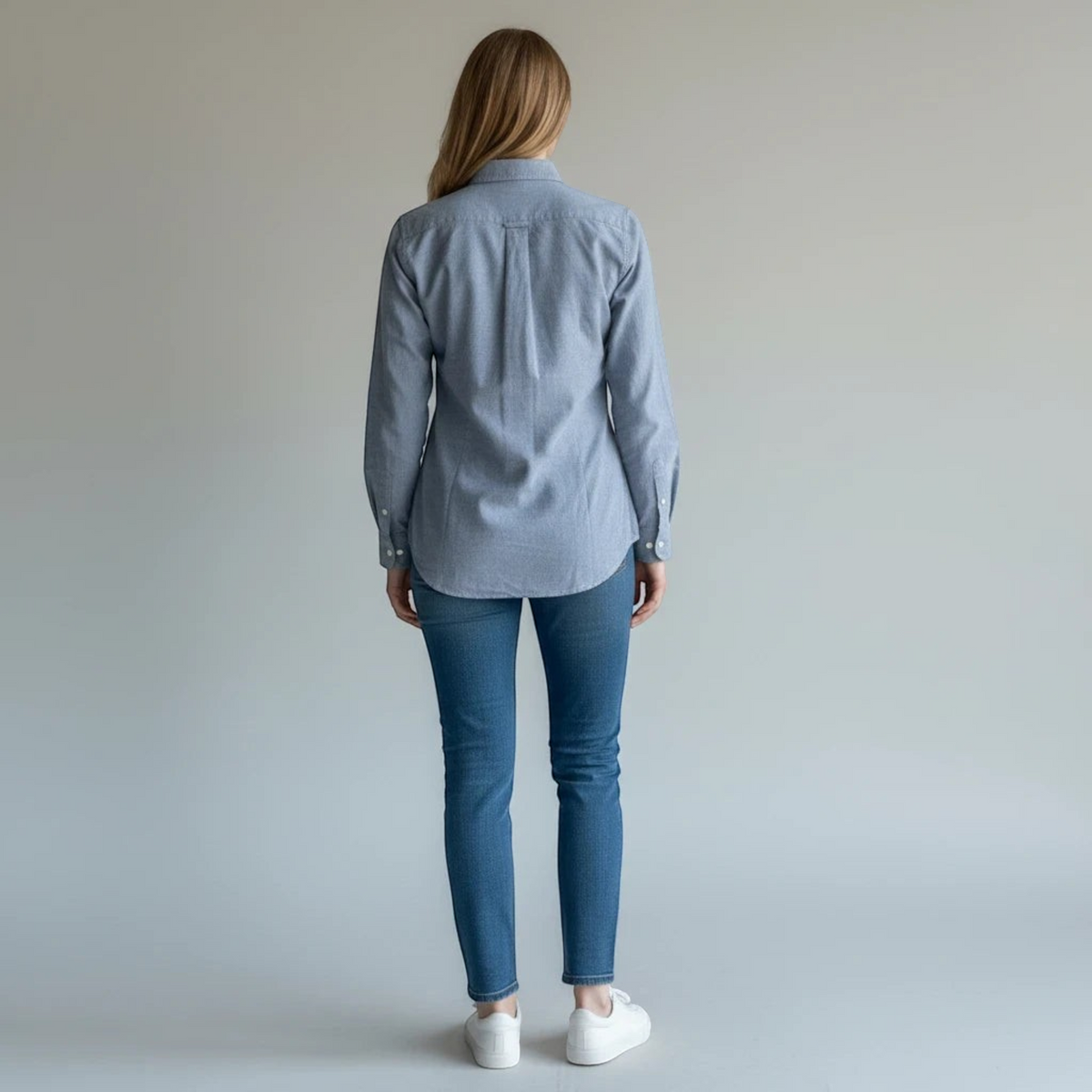 Kobieta tyłem w niebieskiej koszuli z długim rękawem sweet_szop Polo Ralph Lauren, jeansach i białych sneakersach